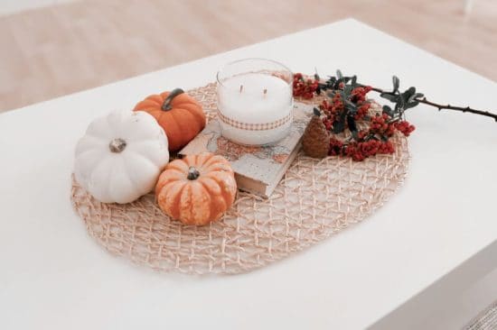 Mini pumpkins, a candle and dried flowers on a side table - Easy Fall Decorating Ideas That Are Budget-proof